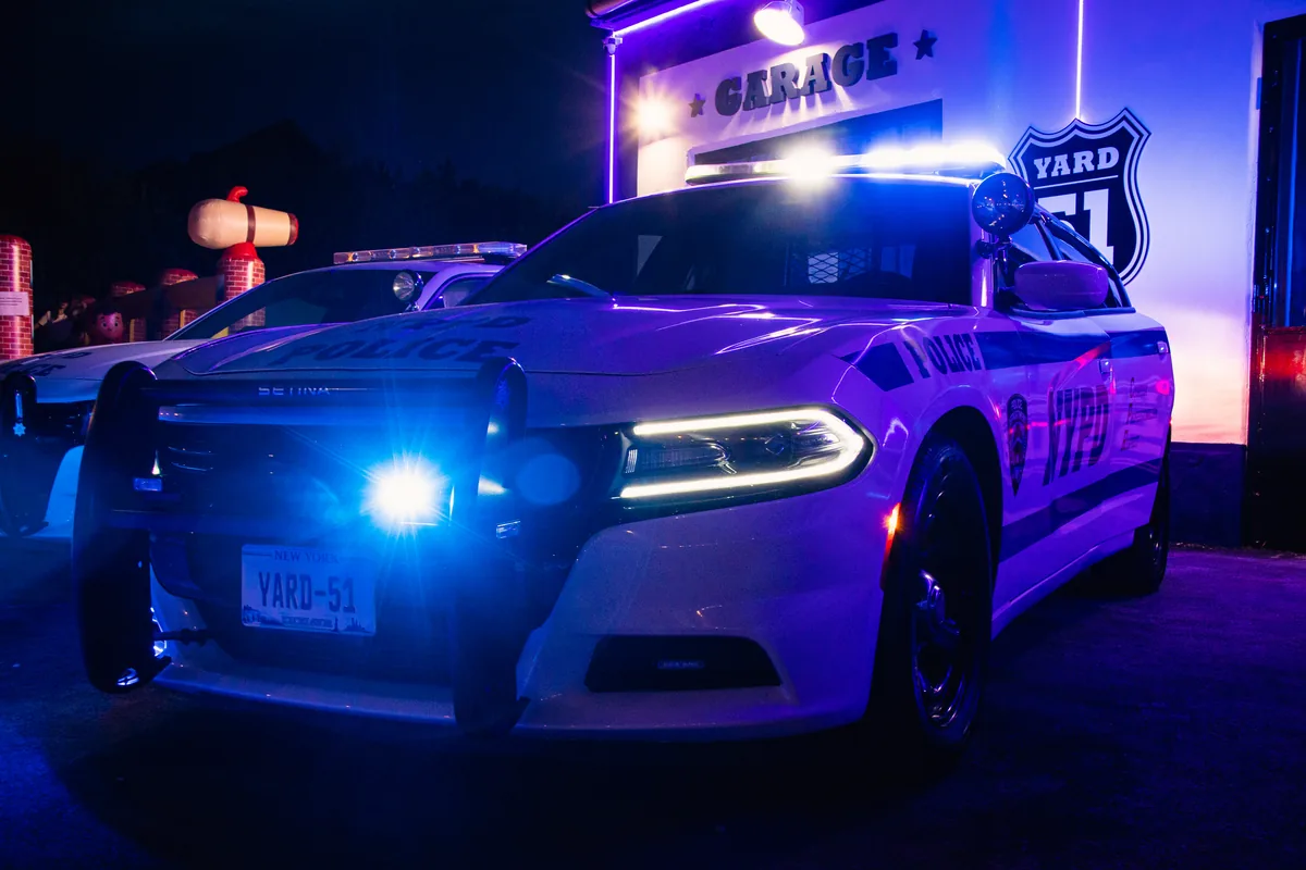 NYPD Dodge Charger bekapcsolt kék villogóval a YARD 51 garázsa előtt éjszaka